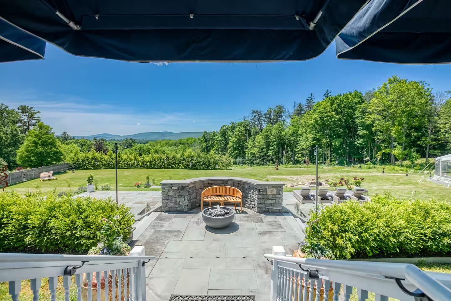 A bluestone terrace with a stone fire pit overlooking the lawn and hills
