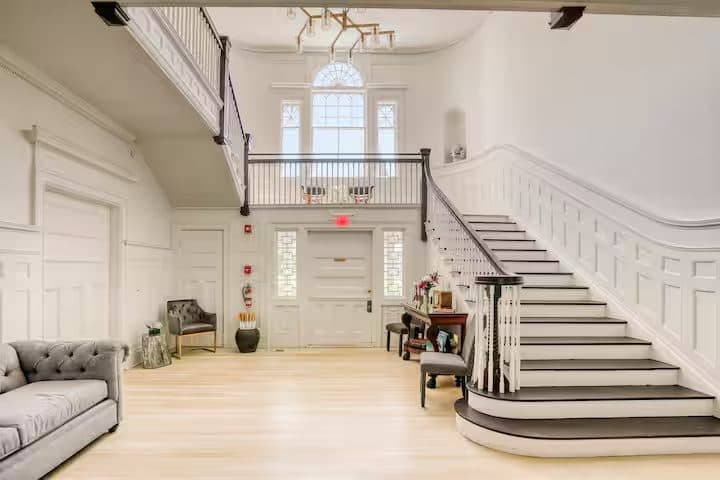 The soaring two-story stair hall with a curved banister and Palladian window